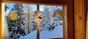 a window with a view of a snow covered forest at Chalet Bergliebe Turrach in Turracher Hohe