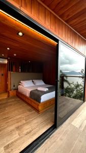 1 dormitorio con 1 cama en el interior de una pared de cristal en Grandi Pousada Sports - Sambaqui - Chalé Jurerê, Chalé da Mole e 3 Cabanas en Florianópolis