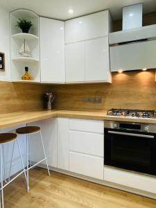 a kitchen with white cabinets and a stove and stools at Family Relax in the Seaside Town with Parking in Hastings