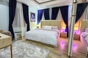 a bedroom with a large bed with blue curtains at Captain's Residence in Abuja