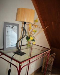 a glass table with a lamp on top of it at Gîtes Bellevue et Mascaret in Courtils