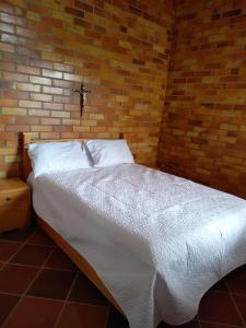 a bed in a room with a brick wall at Cabañas GARUTO in Los Santos