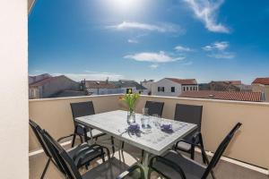 Una mesa y sillas en un balcón con vista. en Tereza, city central modern apartment, en Novalja