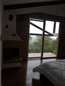 1 dormitorio con cama y ventana grande en Neblina Bird, en Otavalo