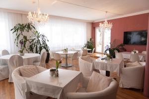 a restaurant with white tables and chairs and chandeliers at HOTEL MARIA in Gramatneusiedl