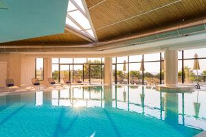 una gran piscina con sillas y ventanas en The Signature Level at Grand Palladium Sicilia Resort & Spa, en Campofelice di Roccella