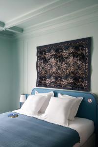 a bed with a blue headboard and white pillows at Hôtel Beauregard in Paris