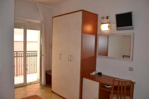 um quarto com uma secretária e um armário com uma televisão em Hotel Ariston em Misano Adriatico