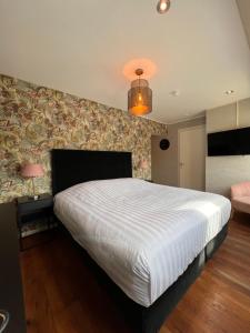 1 dormitorio con 1 cama blanca grande y pared en Herberg de Compagnie en Enkhuizen