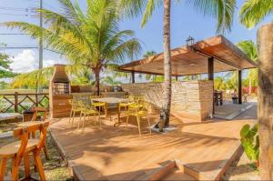 eine Terrasse mit einem Tisch, Stühlen und Palmen in der Unterkunft Village em Itacimirim 5 min a pé da praia. Vista Lagoa! in Itacimirim