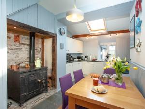 uma cozinha com uma mesa de madeira e um fogão em Mews Cottage em Tintagel