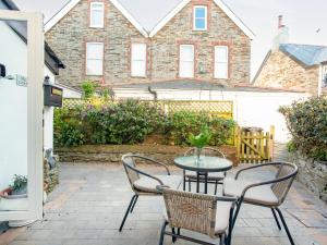 patio ze stołem i krzesłami oraz budynek w obiekcie Mews Cottage w mieście Tintagel