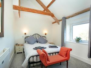 um quarto com uma cama e uma cadeira vermelha em Mews Cottage em Tintagel