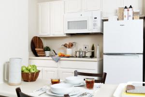 a kitchen with white cabinets and a table with food on it at Intown Suites Extended Stay Atlanta GA - Gwinnett Place in Duluth