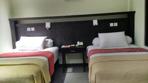 a hotel room with two beds and a table at MAXI HOTEL KEDONGANAN in Kuta