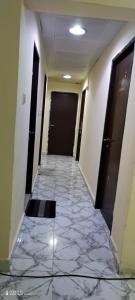 a hallway with a tile floor and a black door at Wummies place in Abu Dhabi