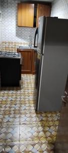 a kitchen with a refrigerator and a tile floor at Wummies place in Abu Dhabi