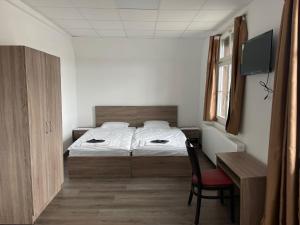 Hotel da Luca في Herzogenbuchsee: غرفة نوم بسرير وكرسي ومكتب
