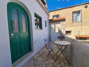 a green door and a table and chairs on a porch at Gythio townhouse in Gythio