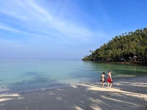 twee mensen lopen op een strand bij het water bij Green Papaya Beach Resort, Koh Phangan in Salad Beach