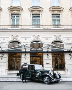 an old car parked in front of a building at Hotel The Peninsula Paris in Paris