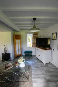 a living room with a tv and a table at Cotswolds Corner Cottage in Moreton in Marsh