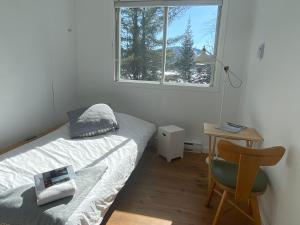 a bedroom with a bed and a desk and a window at Le Couvent Val-Morin in Val-Morin