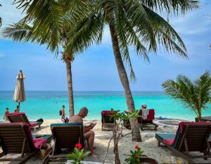 Ein Mann, der am Strand mit Palmen und dem Meer sitzt in der Unterkunft Green Papaya Beach Resort, Koh Phangan in Salad Beach