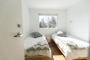 two beds in a white room with a window at Le Couvent Val-Morin in Val-Morin