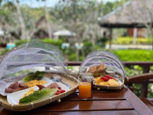 zwei Teller mit Lebensmitteln auf einem Tisch mit Orangensaft in der Unterkunft Green Papaya Beach Resort, Koh Phangan in Salad Beach