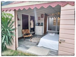 una casa rosa con una mesa y una silla en un porche en LA CABANE D'artiste, en Cul de Sac