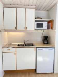 a kitchen with white cabinets and a sink and a microwave at 3:e Sandbank in Beddinge Strand