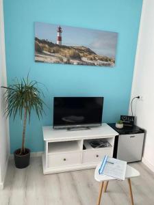 a living room with a white entertainment center with a television at Gästezimmer Lütje Wattwurm in Dornumersiel