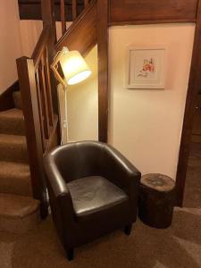 Cette chambre dispose d'une chaise et d'un escalier avec une lampe. dans l'établissement Cosy Cottage next to Farmers Arms Country pub., à Gloucester