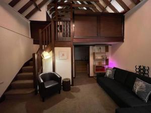 a living room with a couch and a stair case at Cosy Cottage next to Farmers Arms Country pub. in Gloucester