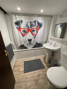 a bathroom with a cow shower curtain and a toilet at Cosy Cottage next to Farmers Arms Country pub. in Gloucester