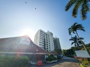 un edificio con una palmera y un edificio en 'Sunny seaview condo' at Regency by Shine Stay, en Port Dickson