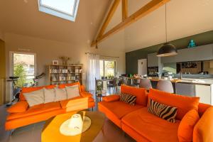 un salon avec des canapés orange et une cuisine dans l'établissement Charmante maison avec Vue LAC et Montagnes - PISCINE privative - LLA Selections by Location lac Annecy, à Saint-Jorioz