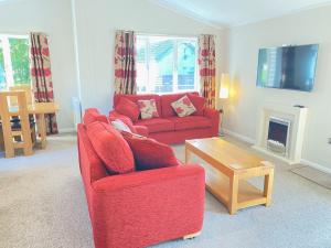 a living room with a red couch and a table at Dalis Den Lodge in Bridlington