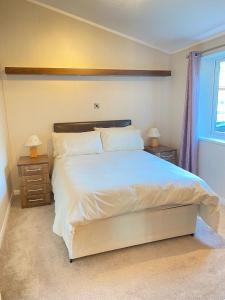 a bedroom with a large white bed with two night stands at Dalis Den Lodge in Bridlington