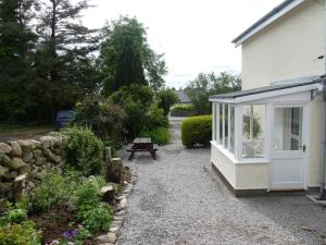 uma casa branca com um banco num jardim em Millfield em Rockcliffe