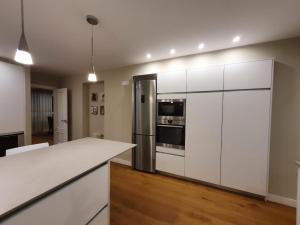 uma cozinha com armários brancos e um frigorífico de aço inoxidável em Magnifico piso centro ciudad em La Coruña