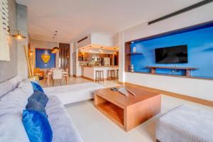 a living room with a white couch and a large tv at Aldea Thai Beachfront Condo Complex with Resort Pool & Amenities in Playa del Carmen