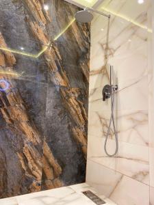 Un baño con ducha con pared de piedra. en Bel appartement avec une belle vue sur la grande mosquée Hassan II et la mer, en Casablanca