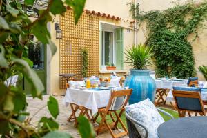een patio met tafels en stoelen en een blauwe vaas bij La Maison d'été in Salon-de-Provence