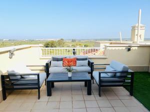 un patio con un divano, 2 sedie e un tavolo di Ático de lujo - Luxury Penthouse a Huelva
