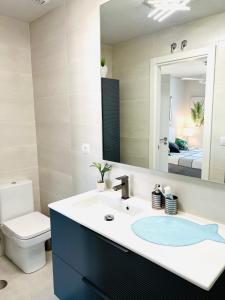 W łazience znajduje się umywalka, toaleta i lustro. w obiekcie Ático de lujo - Luxury Penthouse w mieście Huelva