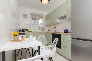 kuchnia z zielonymi szafkami oraz białym stołem i krzesłami w obiekcie Metro Bemowo Two-Storey Apartment Pełczyńskiego by Renters w Warszawie