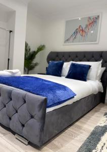 a large bed with blue pillows on top of it at Stylish Cosy Studio Apartment in Kent