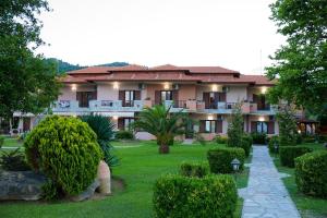 a large building with a garden in front of it at Stamos Apartments and Studios in Vourvourou